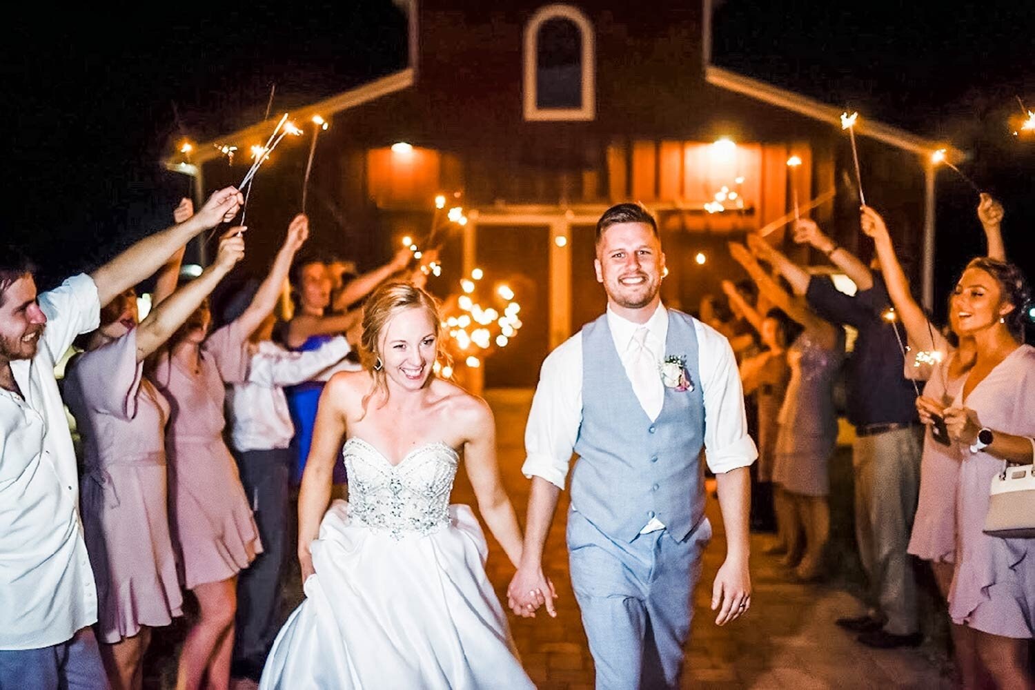Newlyweds leaving the barn beneath a sparkling send-off