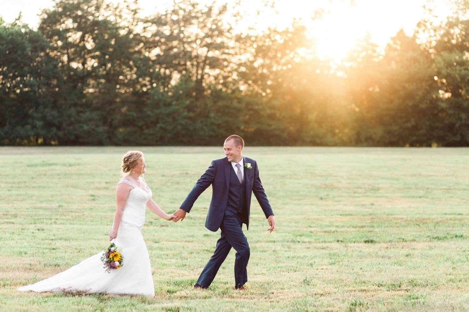 A newly married couple walking through the farm at sunset